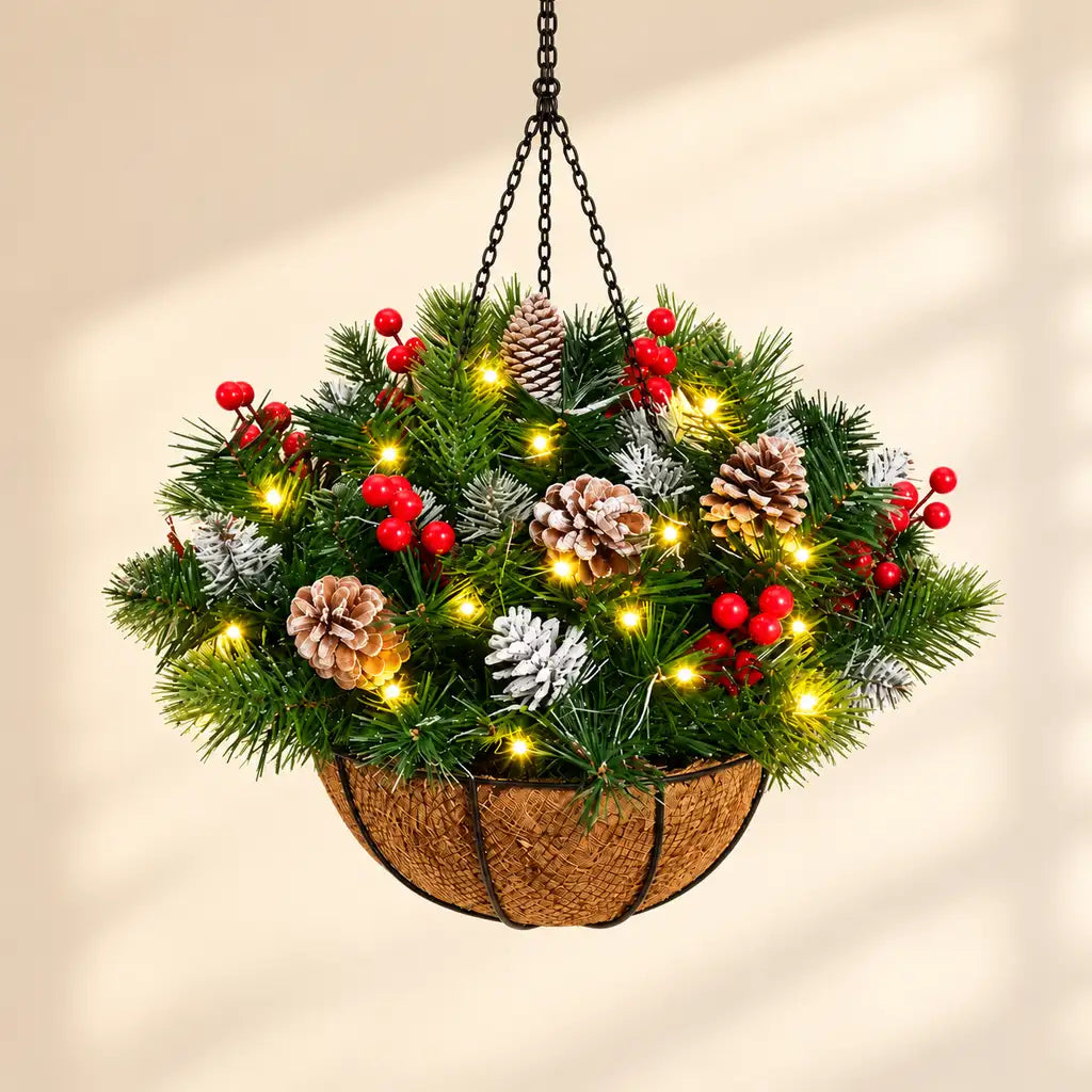 Illustrative product view: Pinecone holiday hanging basket with frosted greenery, red berries and warm lights against a warm neutral background.