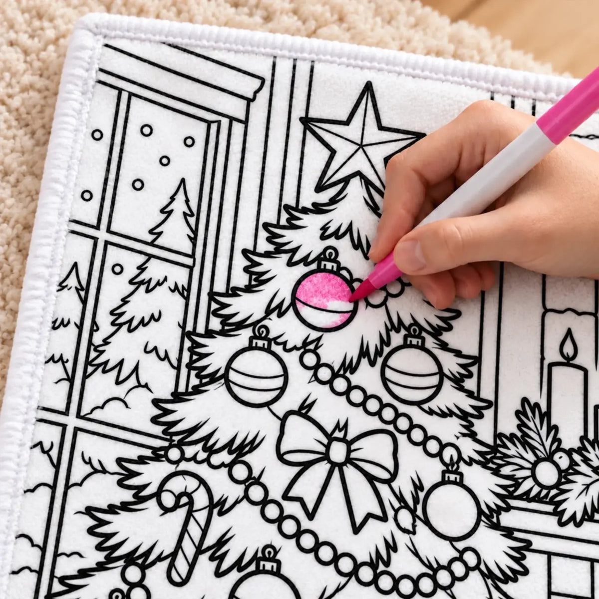 Close-up of a pink marker coloring an ornament on a Christmas doodle blanket
