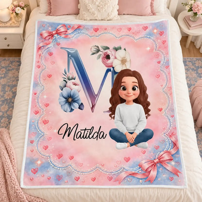 Pink floral monogram girl blanket displayed across a bed