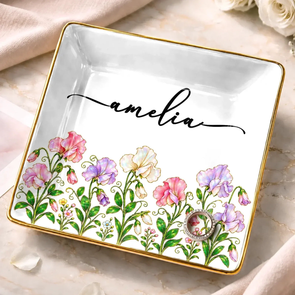 Square white jewelry dish with pink and purple flowers, a gold-tone border and the name Amelia