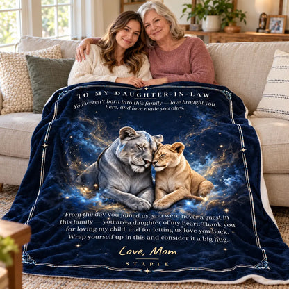Mother-in-law and adult daughter-in-law sharing the navy lion gift blanket on a sofa, with Love, Mom message.
