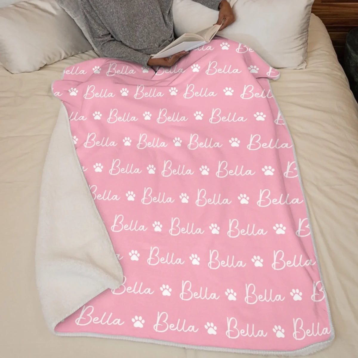 Pink paw-print and name blanket displayed on a bed