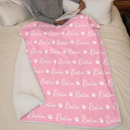 Pink paw-print and name blanket displayed on a bed