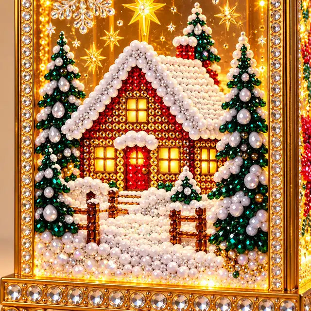 Illustrative product view: Close-up of the completed lantern's snowy cottage artwork, showing faceted gems, evergreen trees and gold-and-crystal trim.