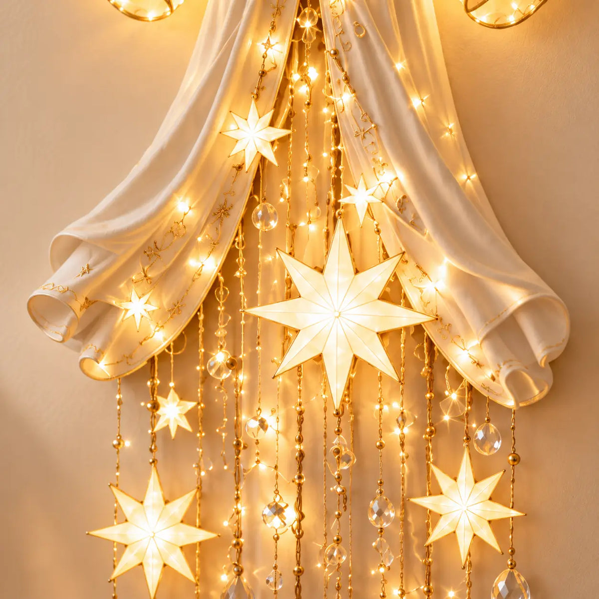 Illustrative product view: Close-up of the Starfall angel's warm glowing stars, fine gold-tone strands and clear hanging beads beneath its ivory robe.